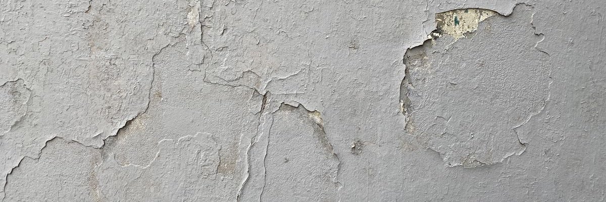 Wide view of a weathered painted wall surface with cracked and lifting layers